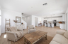 open-concept space with a large white couch, accent chairs, and a wooden rustic coffee table 