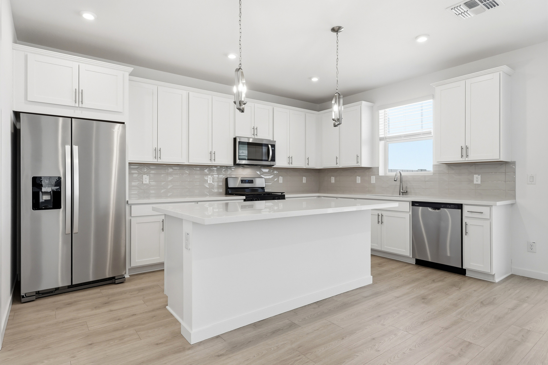 open-concept kitchen with white cabinets, quartz countertops, and stainless-steel appliances