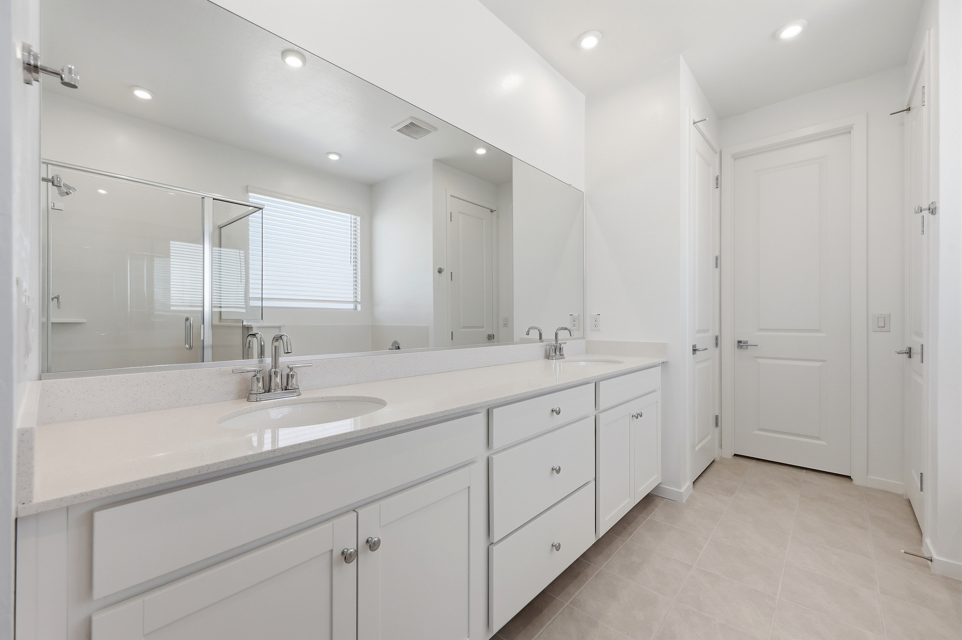 spacious bathroom with double sink, white cabinets, and chrome faucets
