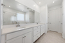 spacious bathroom with double sink, white cabinets, and chrome faucets