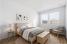 spacious bedroom with a full-sized bed, an oak nightstand, a beige rug, and an oak accent chair