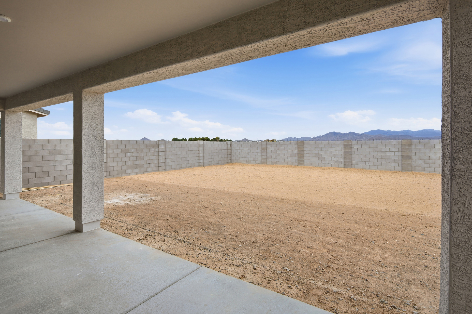 spacious dirt backyard with a concrete block wall