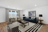 open-concept space with a large navy-blue couch, brown coffee table, and grey accent chairs