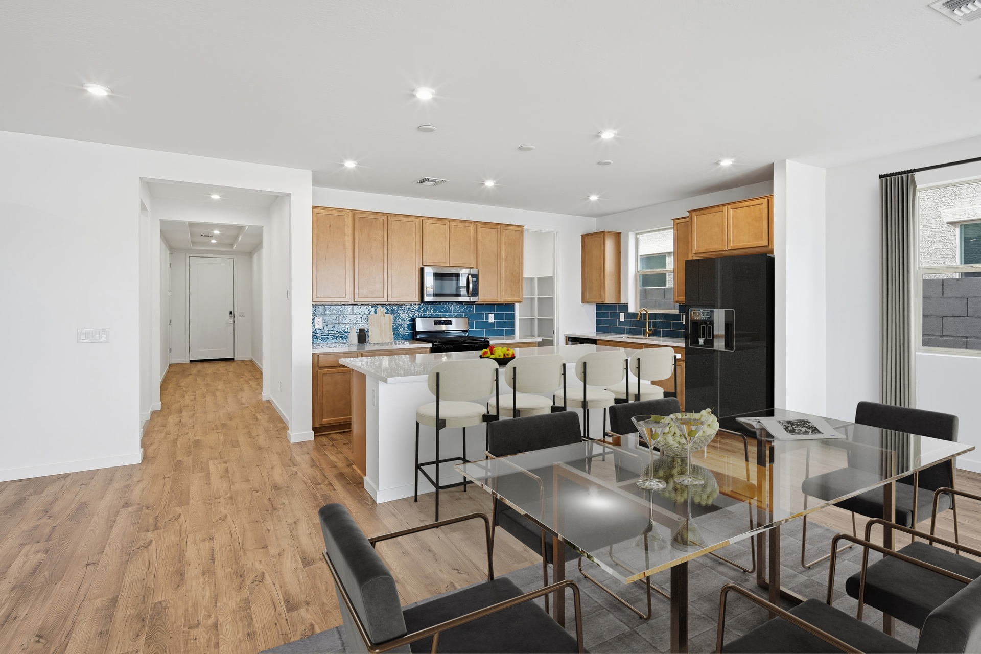spacious kitchen with light brown cabinets, white barstools, and stainless-steel appliances