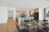 spacious kitchen with light brown cabinets, white barstools, and stainless-steel appliances