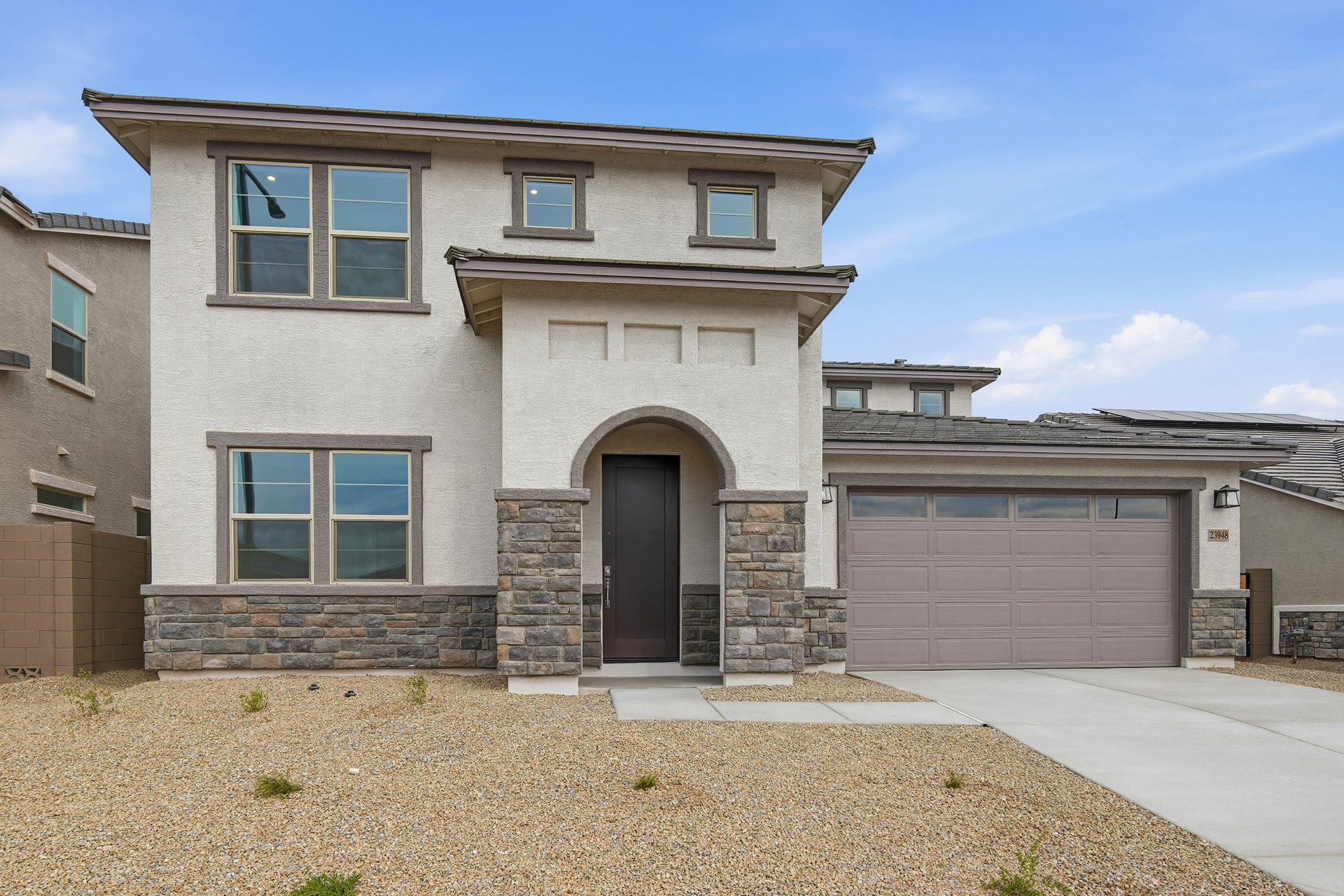 two-story single-family home with desert landscaping and a concrete driveway