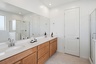spacious bathroom with light brown cabinets, white countertops, and chrome faucets