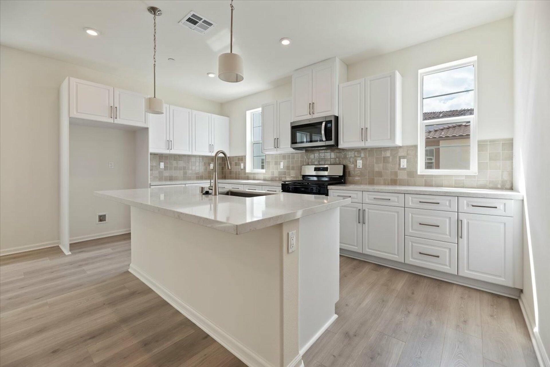 kitchen featuring an island with an attached sink and white cabinets