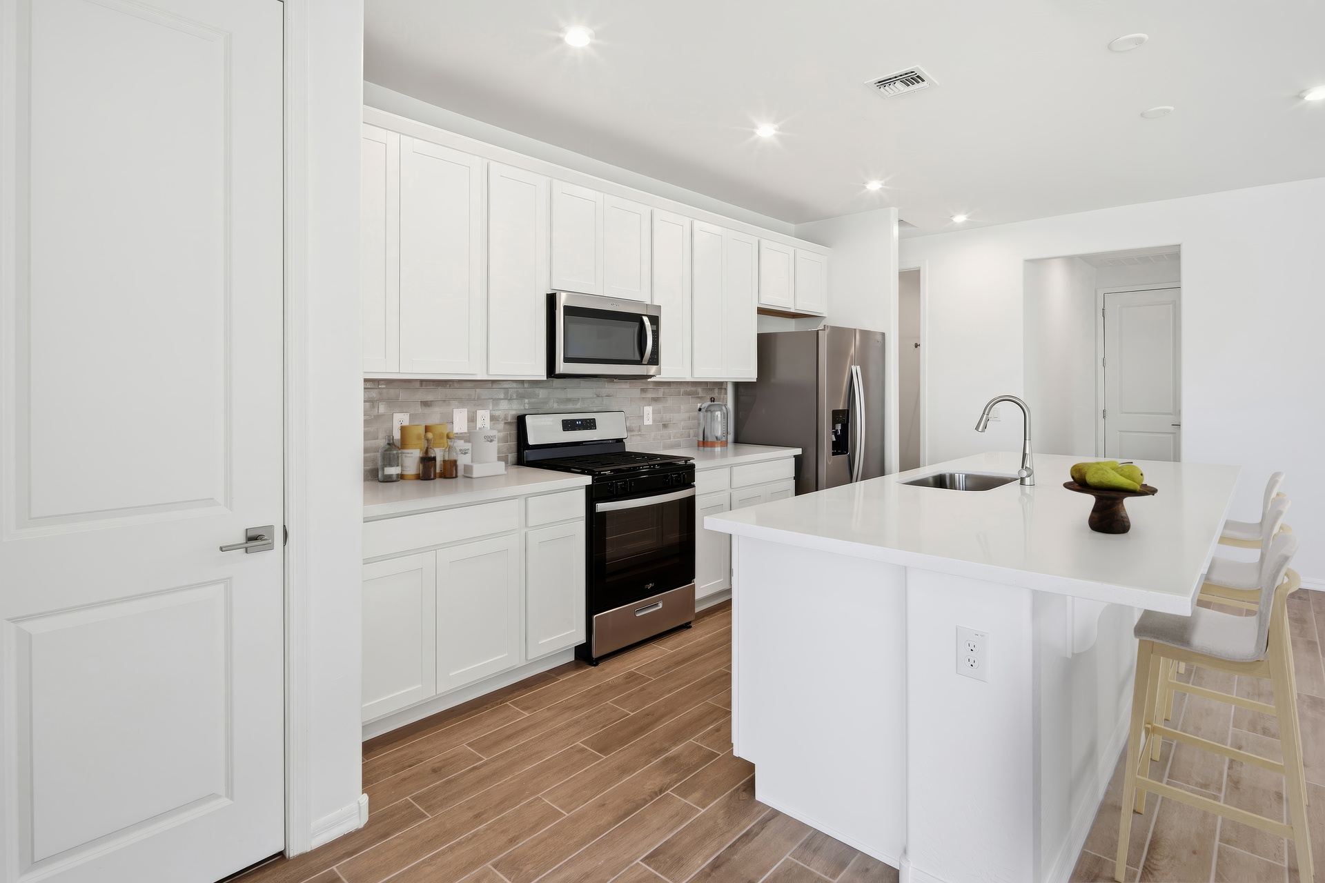 kitchen with white quartz countertops, wooden barstools, and stainless-steel appliances