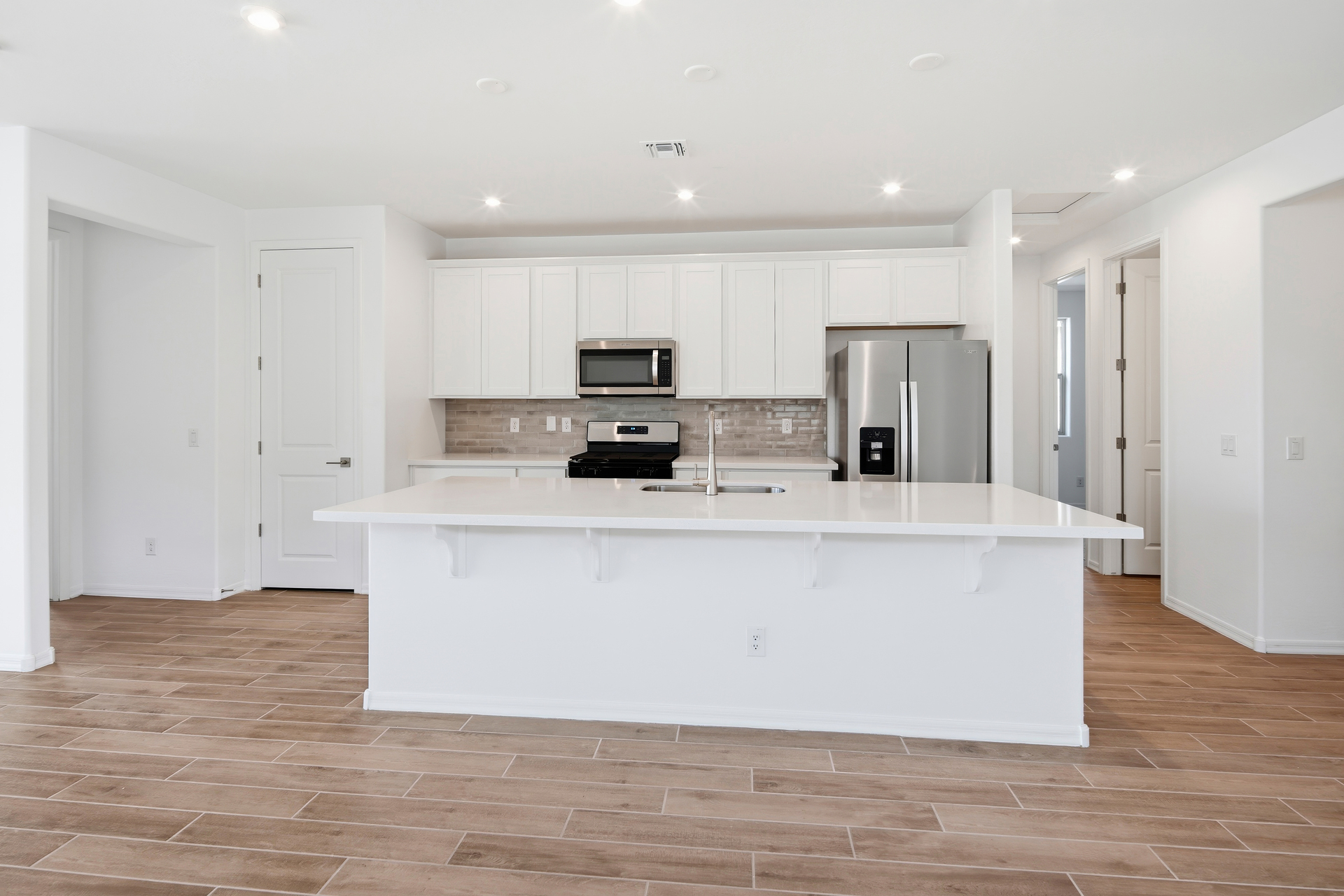 spacious kitchen with white quartz countertop, white cabinets, and stainless-steel appliances