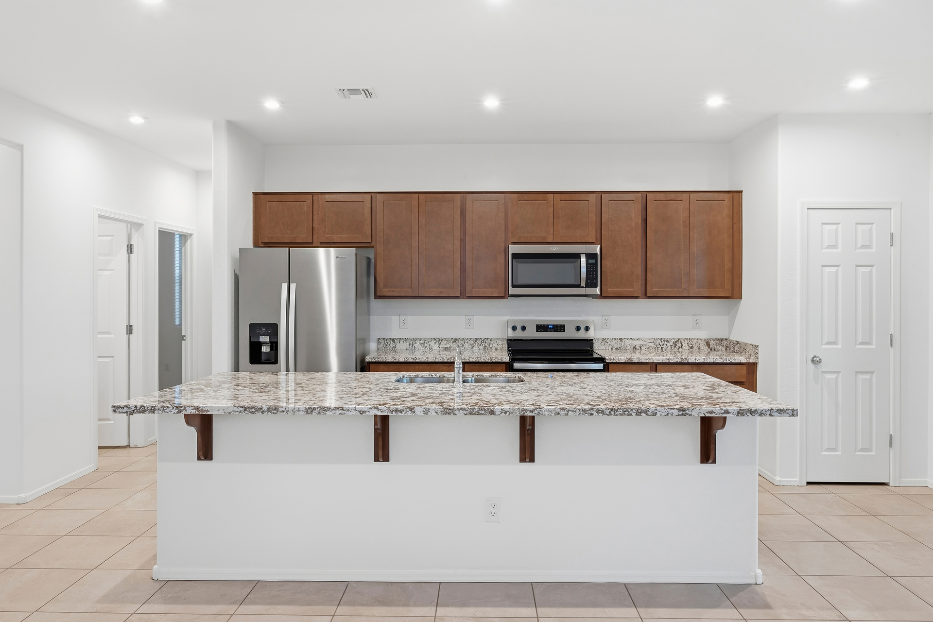 kitchen with tile flooring, granite countertops, and brown cabinets