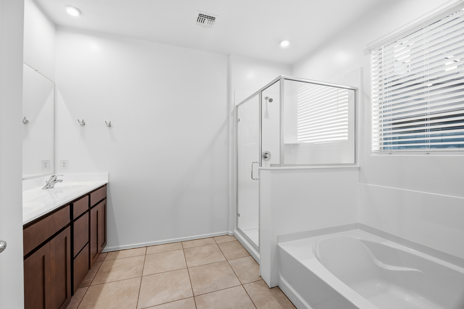 bathroom with walk-in shower, soaking tub, and brown cabinets