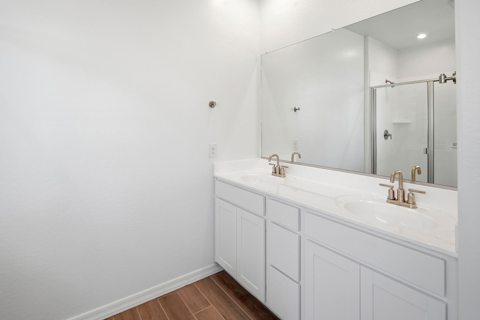 spacious bathroom with wood-like flooring, white cabinets, and white countertop