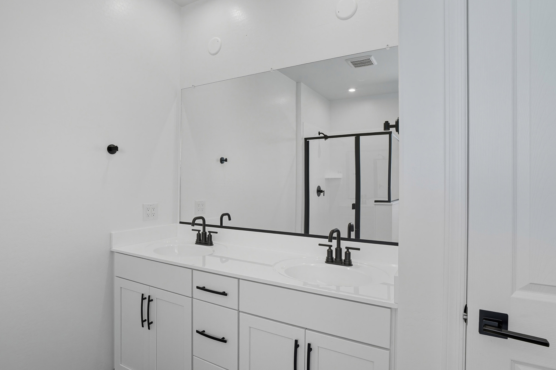 bathroom with a double sink, white countertops, and black faucets