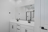 bathroom with a double sink, white countertops, and black faucets