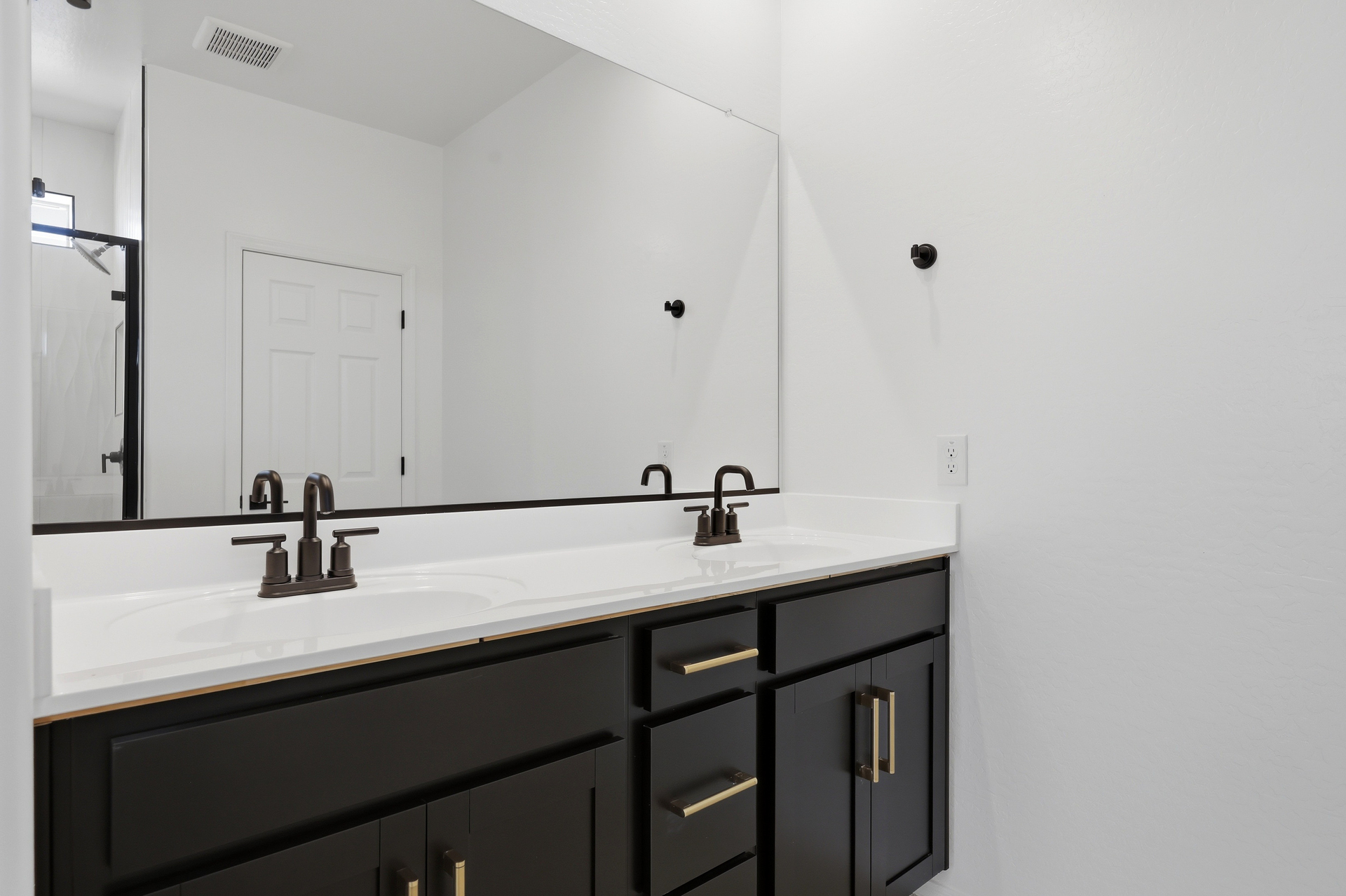 spacious bathroom with a double sink, black cabinets, and matte black faucets