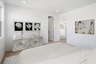 large bed with neutral tones, black and white artwork on the wall, and a white dresser