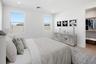 large bed with neutral tones, black and white artwork on the wall, and a white dresser