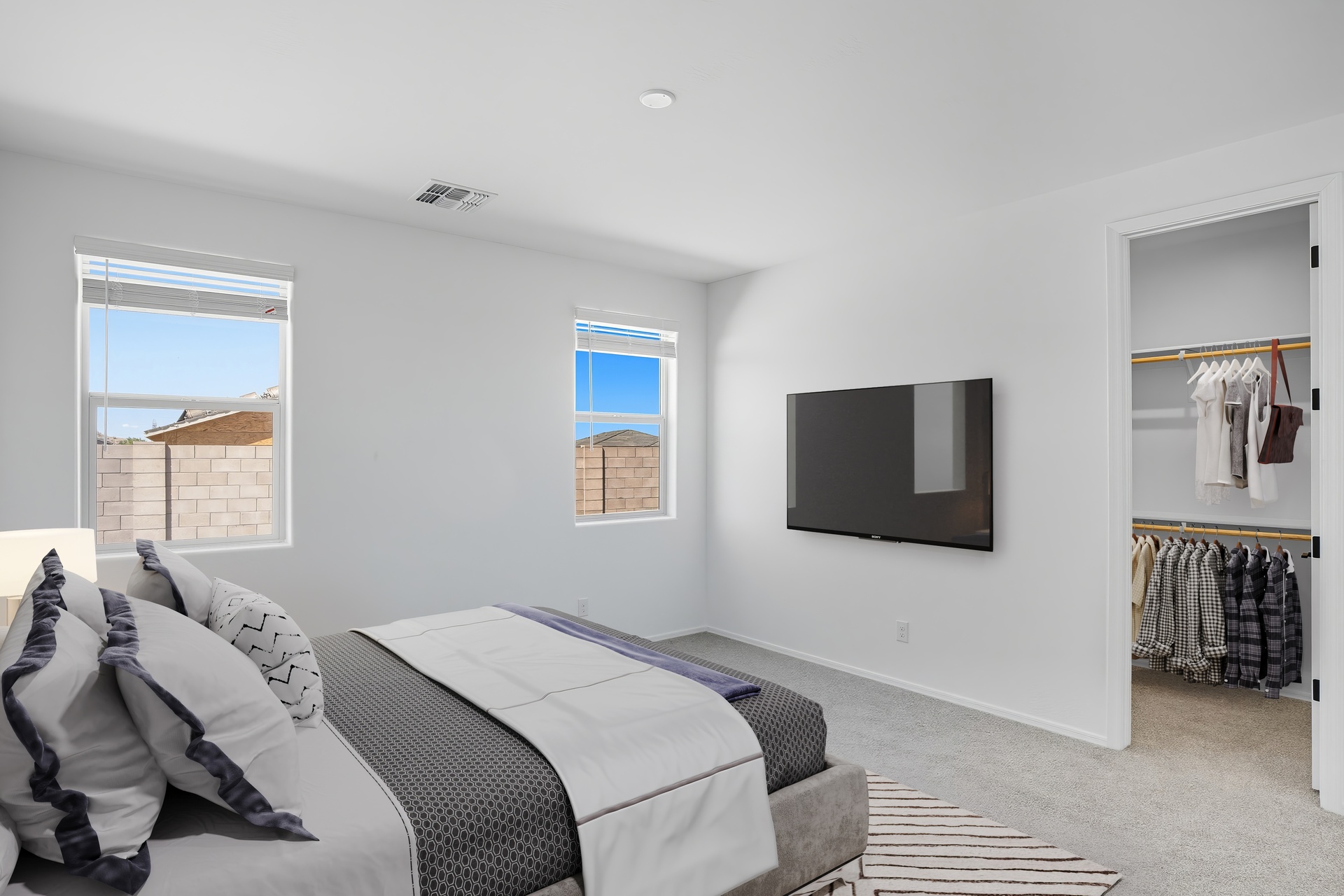 spacious bedroom with a large bed and tv mounted on the wall