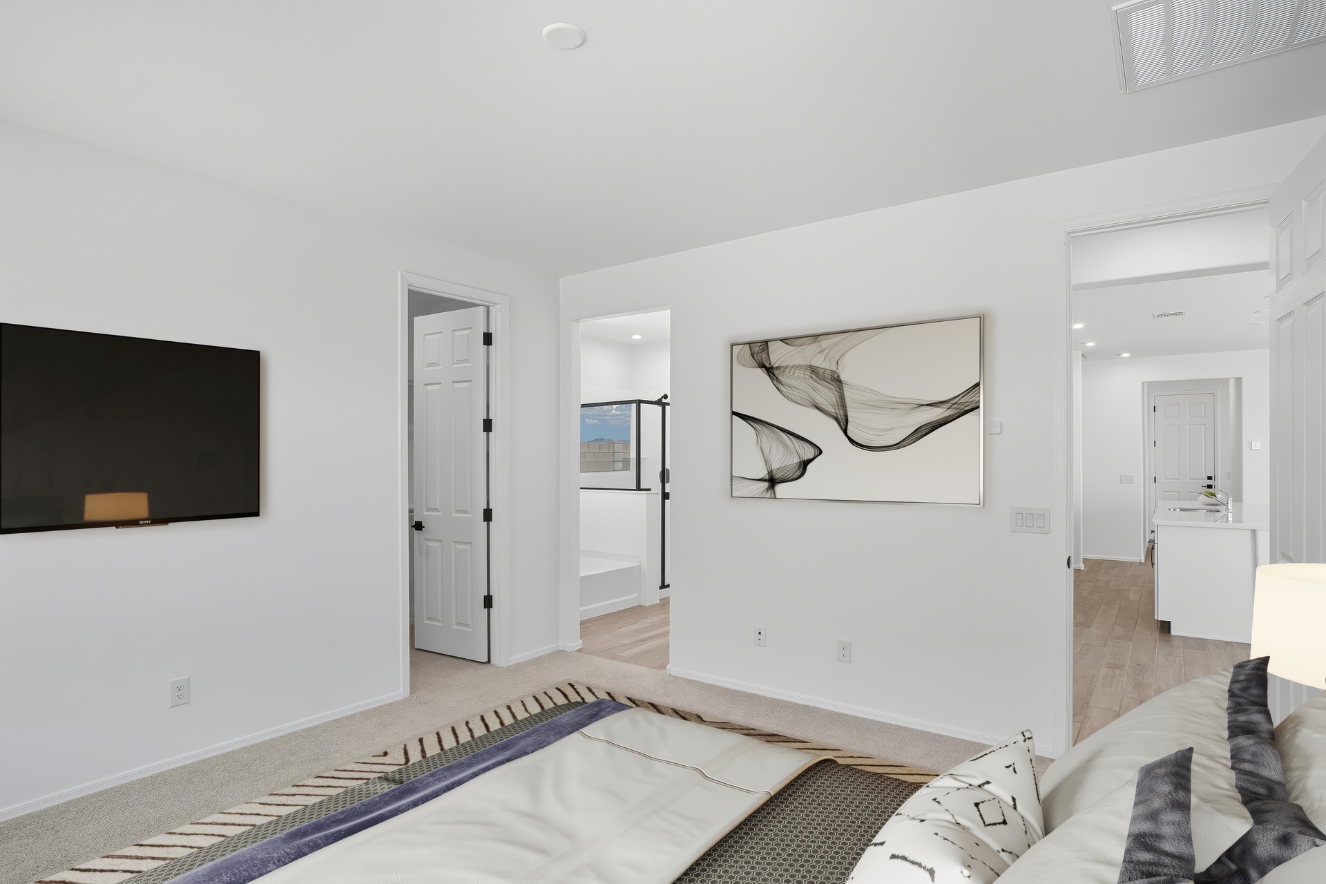 spacious bedroom with a large bed and tv mounted on the wall