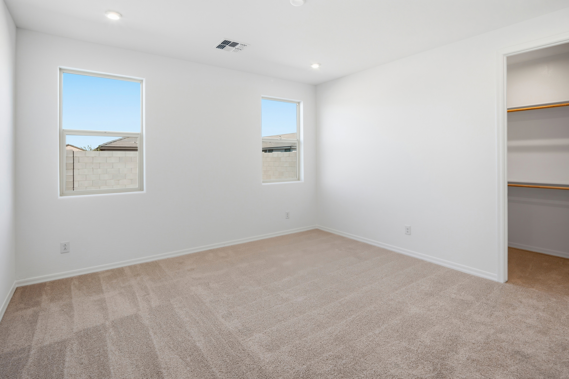 spacious bedroom with light brown carpet and plenty of natural light