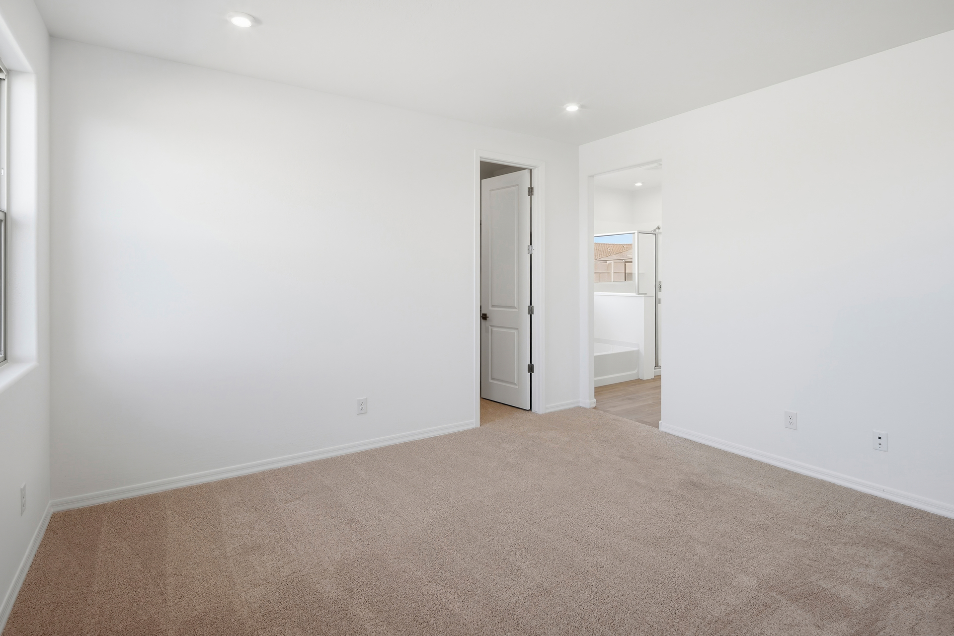 spacious bedroom with light brown carpet and plenty of natural light