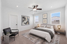 spacious bedroom with a king-sized bed with oak nightstands, a black accent chair, and a grey duvet