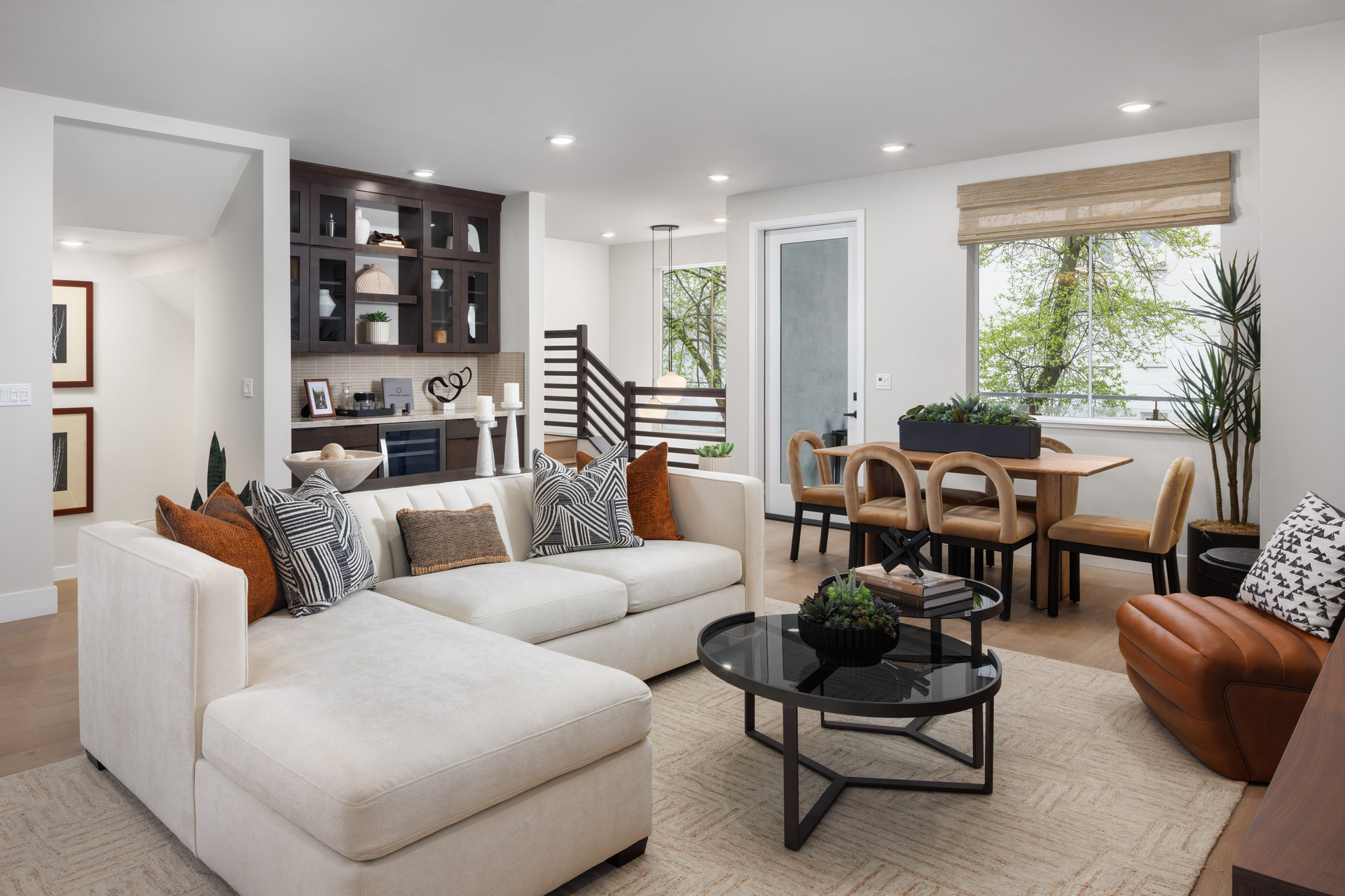 great room with white sofa & orange pillows, black coffee table, built-in beverage bar with espresso cabinets, window, and brown leather chair