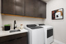 laundry room with espresso cabinets, white washer & dryer, and sink