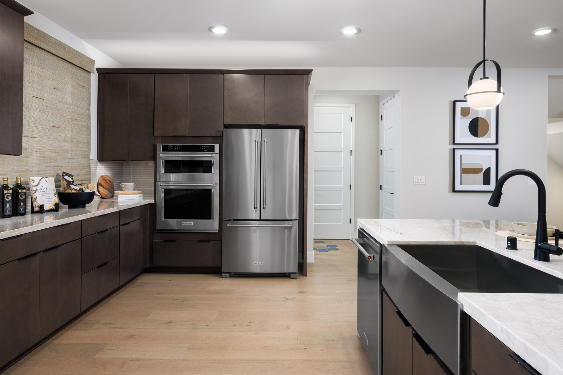 kitchen with espresso cabinets, light quartz counters, stainless-steel appliances, and light wood floors