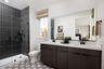 bathroom with espresso cabinets, white counters, two sinks, black tiled walk-in shower, and window above toilet