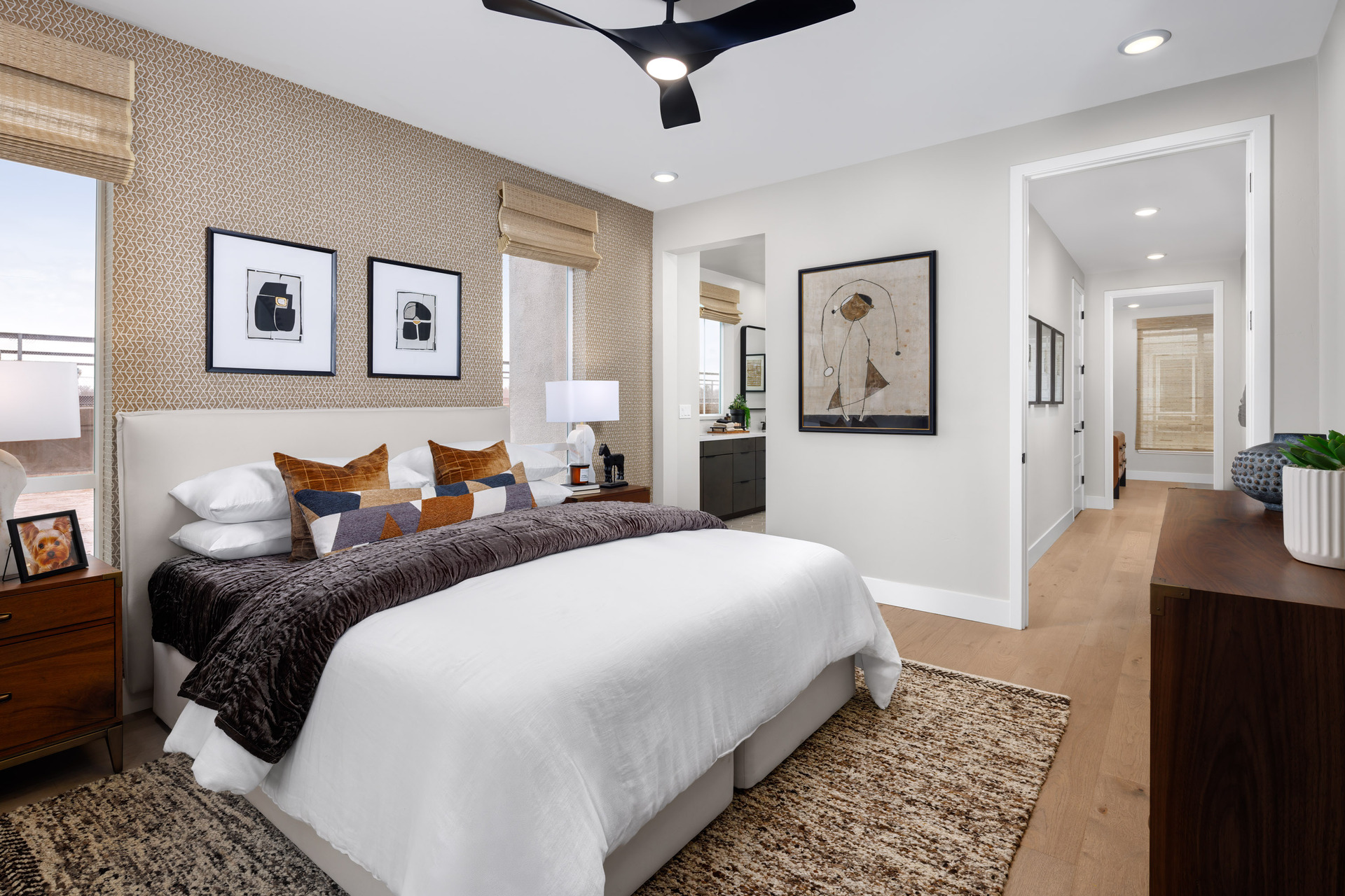 bedroom with white upholstered bed, tan wallpaper, black ceiling fan, and wood nightstands
