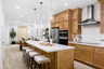 kitchen with light wood cabinets, white counters, island, and stainless-steel hood above stove