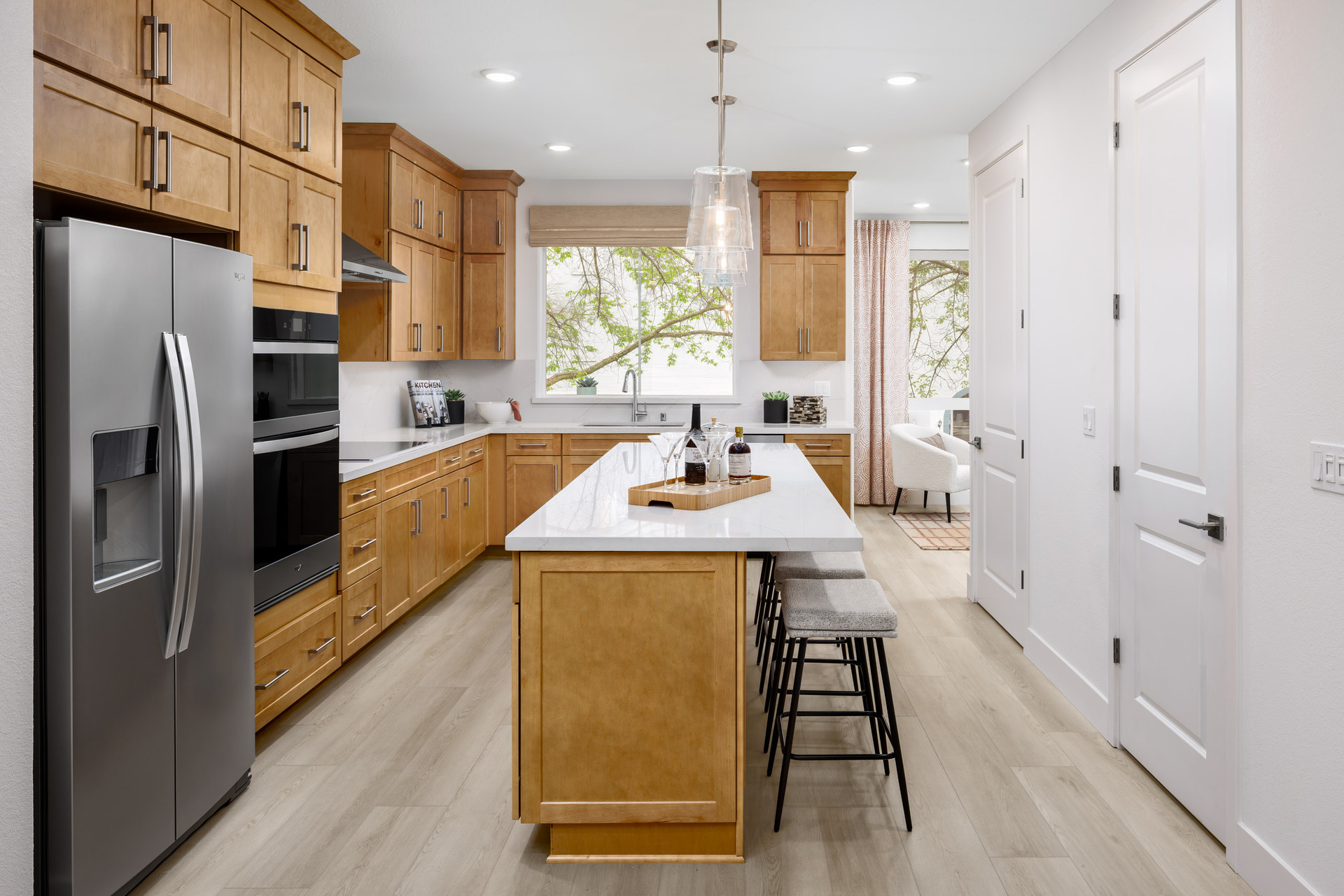 kitchen with light wood floors & cabinets, island, white counters, window above sink, and stainless-steel appliances
