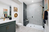 bathroom with green cabinets, white counter, light gray tile floors, and large walk-in shower with frameless glass enclosure