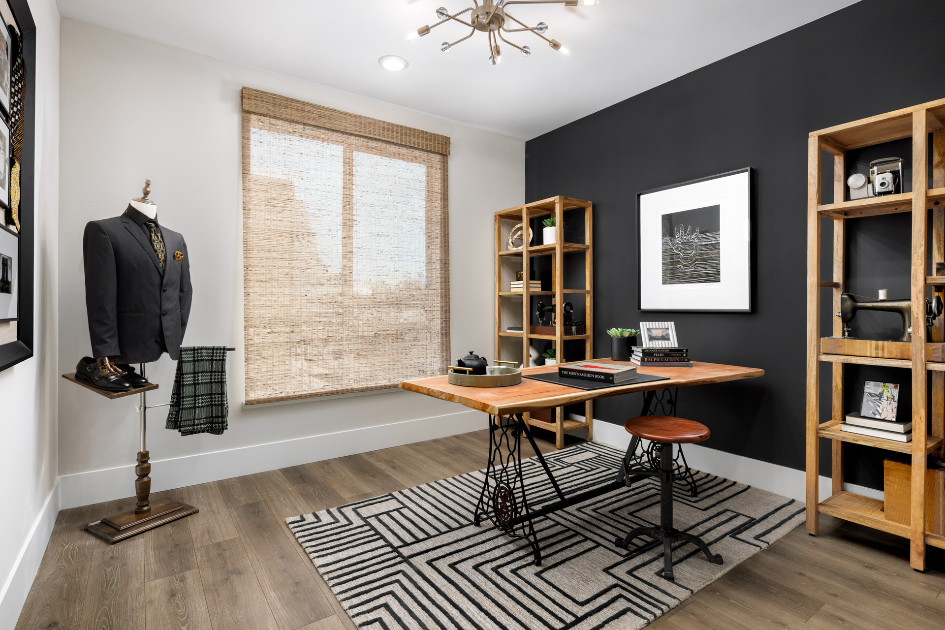 bedroom being used as office with wood floors, wood desk and stool, black accent wall, two wood bookcases and window