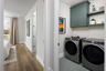 laundry room with gray front load washer & dryer, green cabinets & shelves, and tile floors