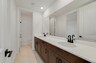second bathroom with dual sinks and brown cabinets