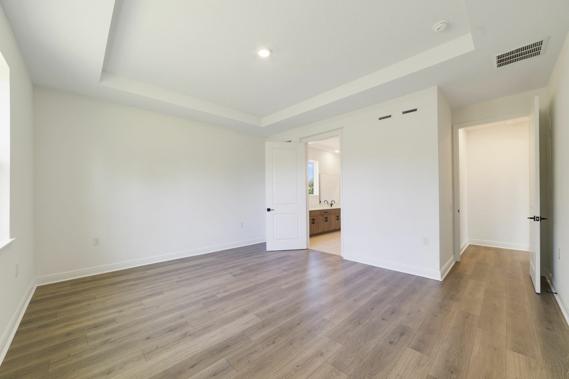 tray ceilings and hardwood vinyl plank with multiple windows. 