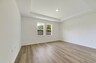 tray ceilings and hardwood vinyl plank with multiple windows. 