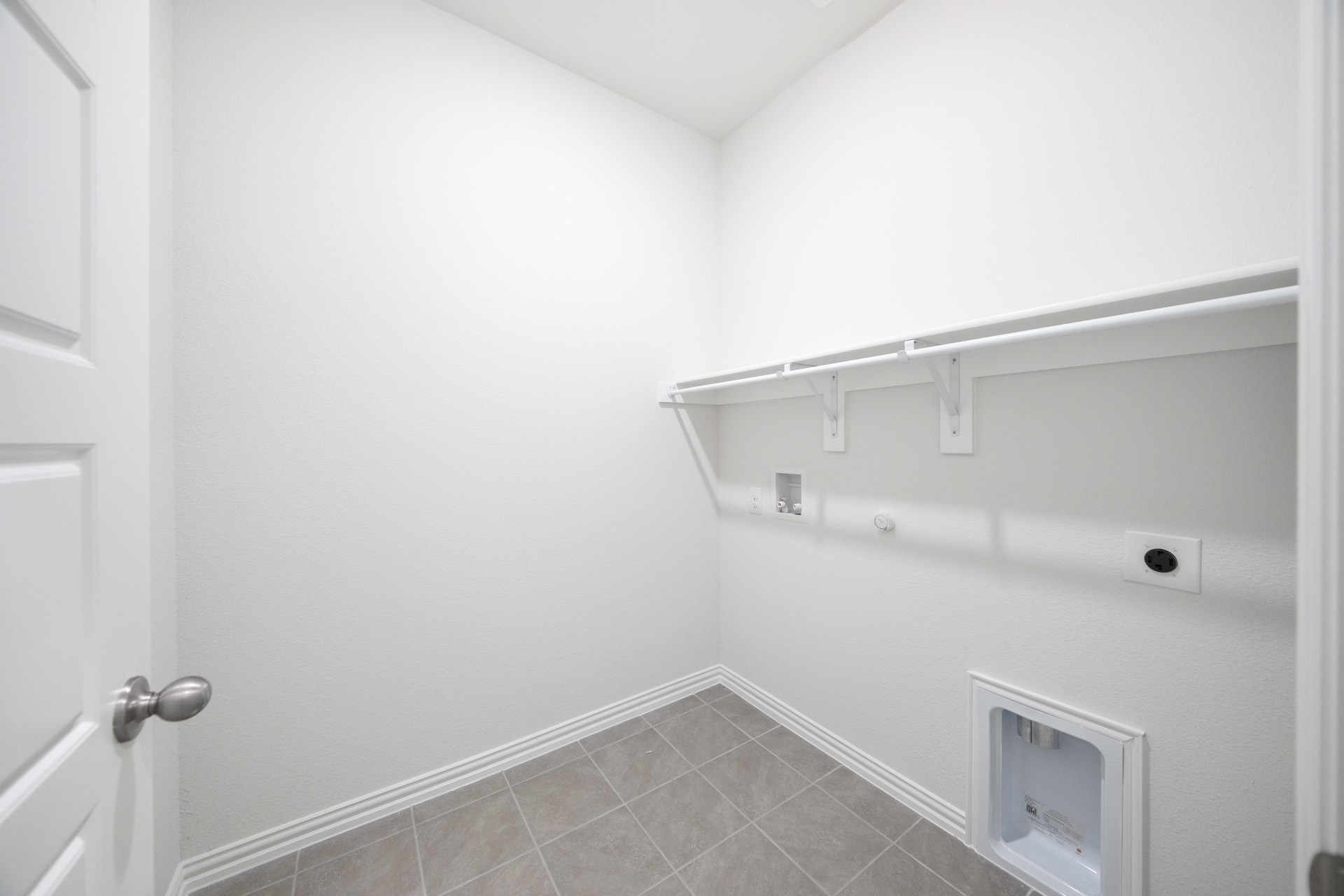 laundry room with tile flooring and storage shelf