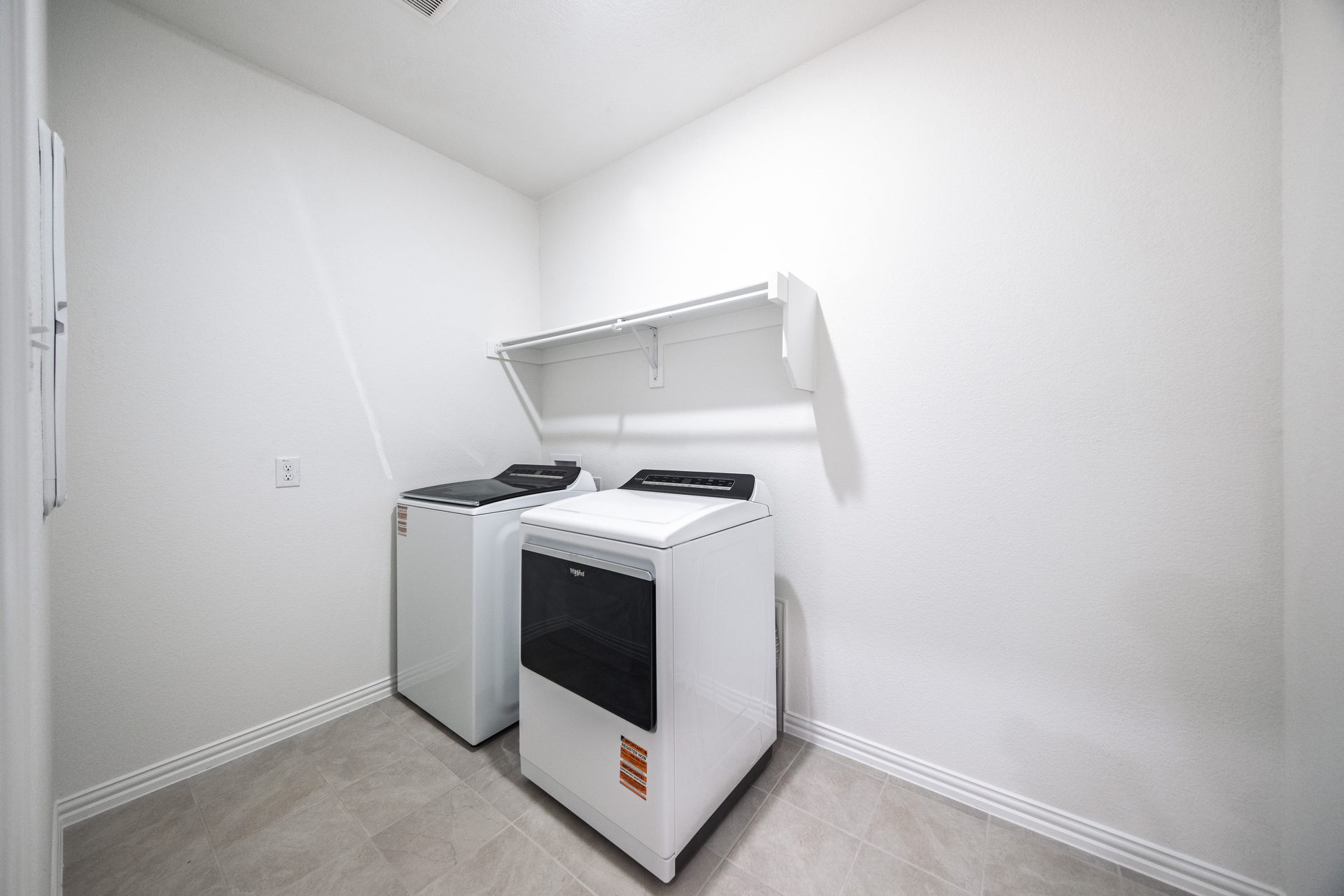 spacious laundry room with tile flooring and storage shelf
