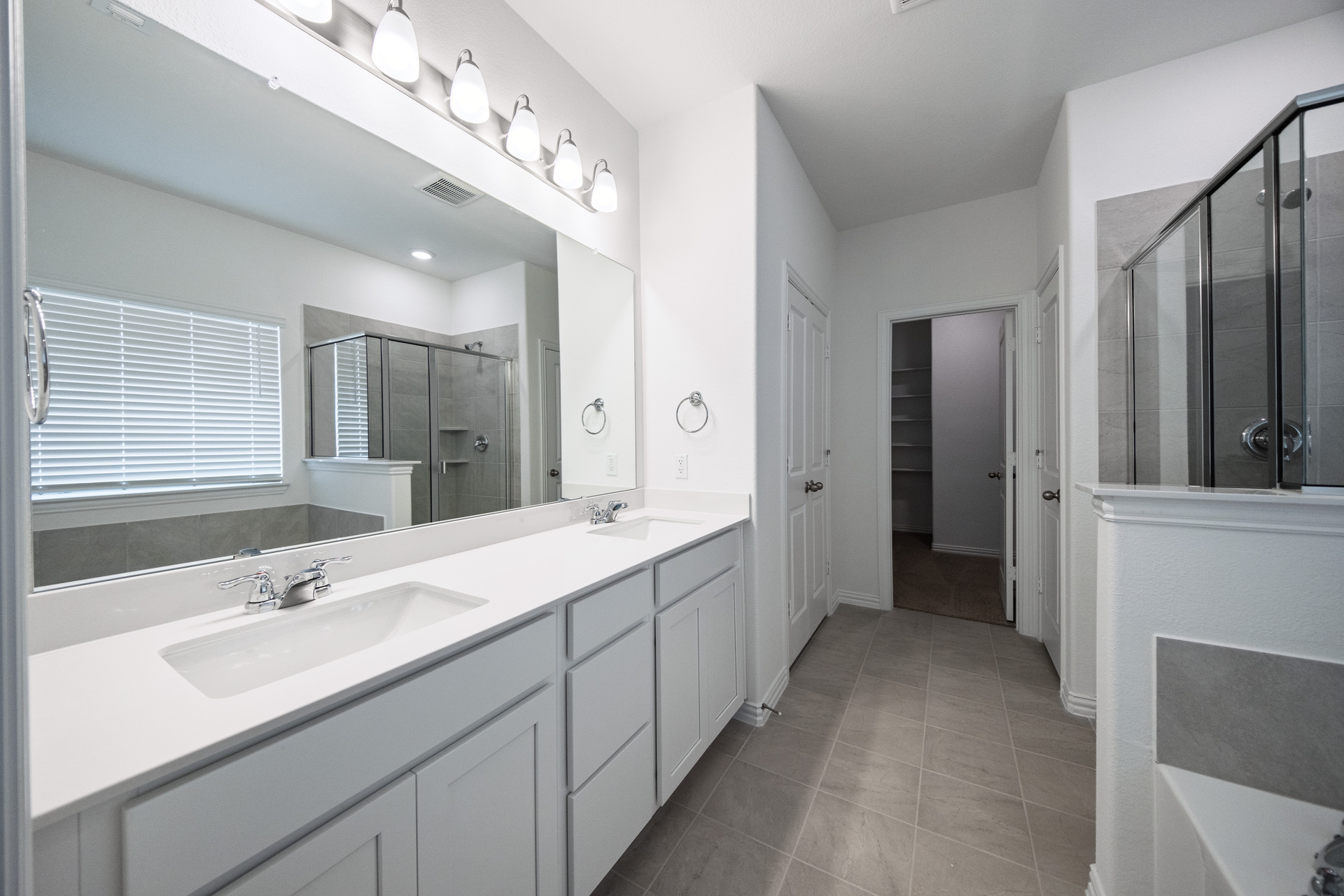 primary bathroom with double sinks and tile flooring