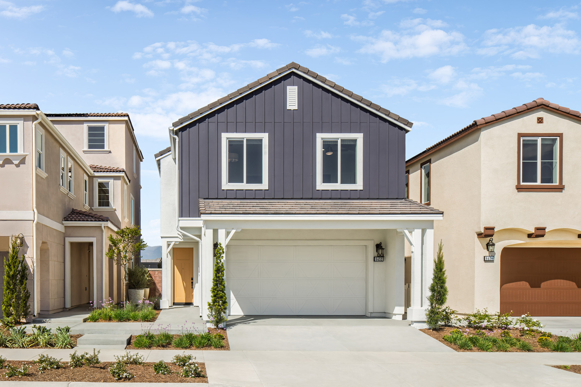 exterior of two-story home with orange door and desert landscaping
