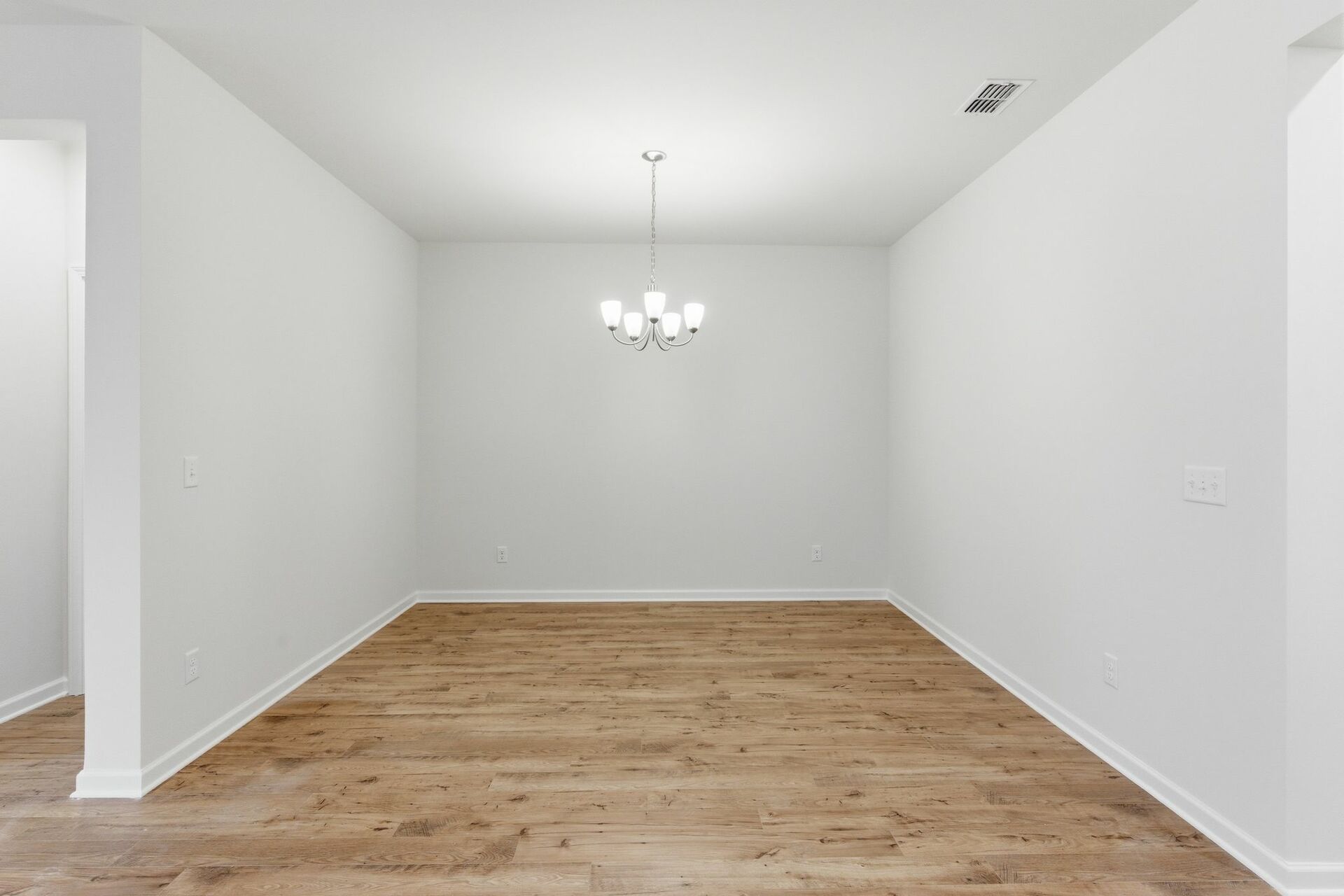 dining room with wood flooring, large light fixture, and a view of the kitchen