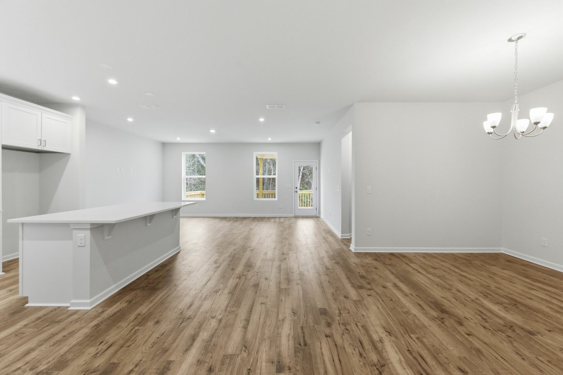 dining room with wood flooring, large light fixture, and a view of the kitchen