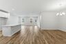 dining room with wood flooring, large light fixture, and a view of the kitchen
