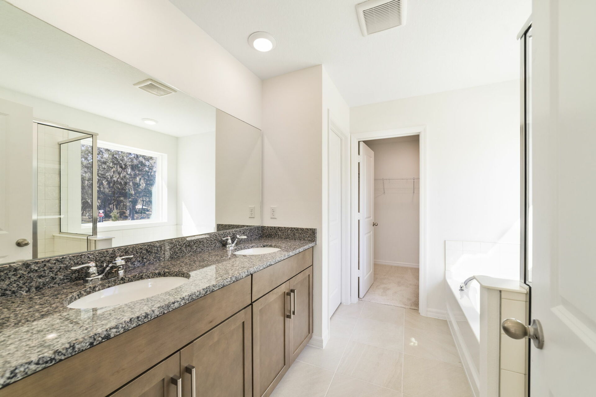 dual sink vanity with mirror, shower, and a separate tub