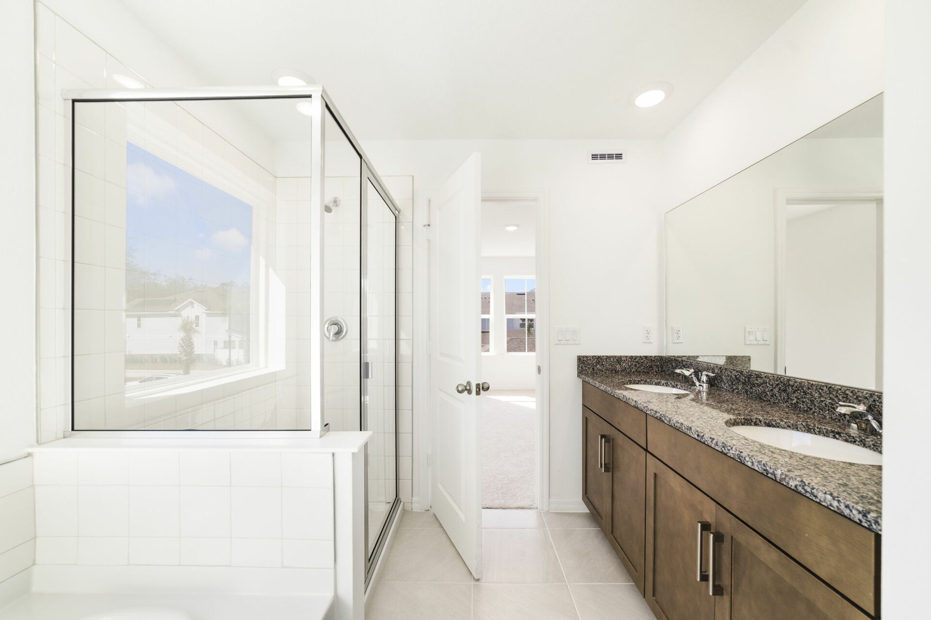 dual sink vanity with mirror, shower, and a separate tub