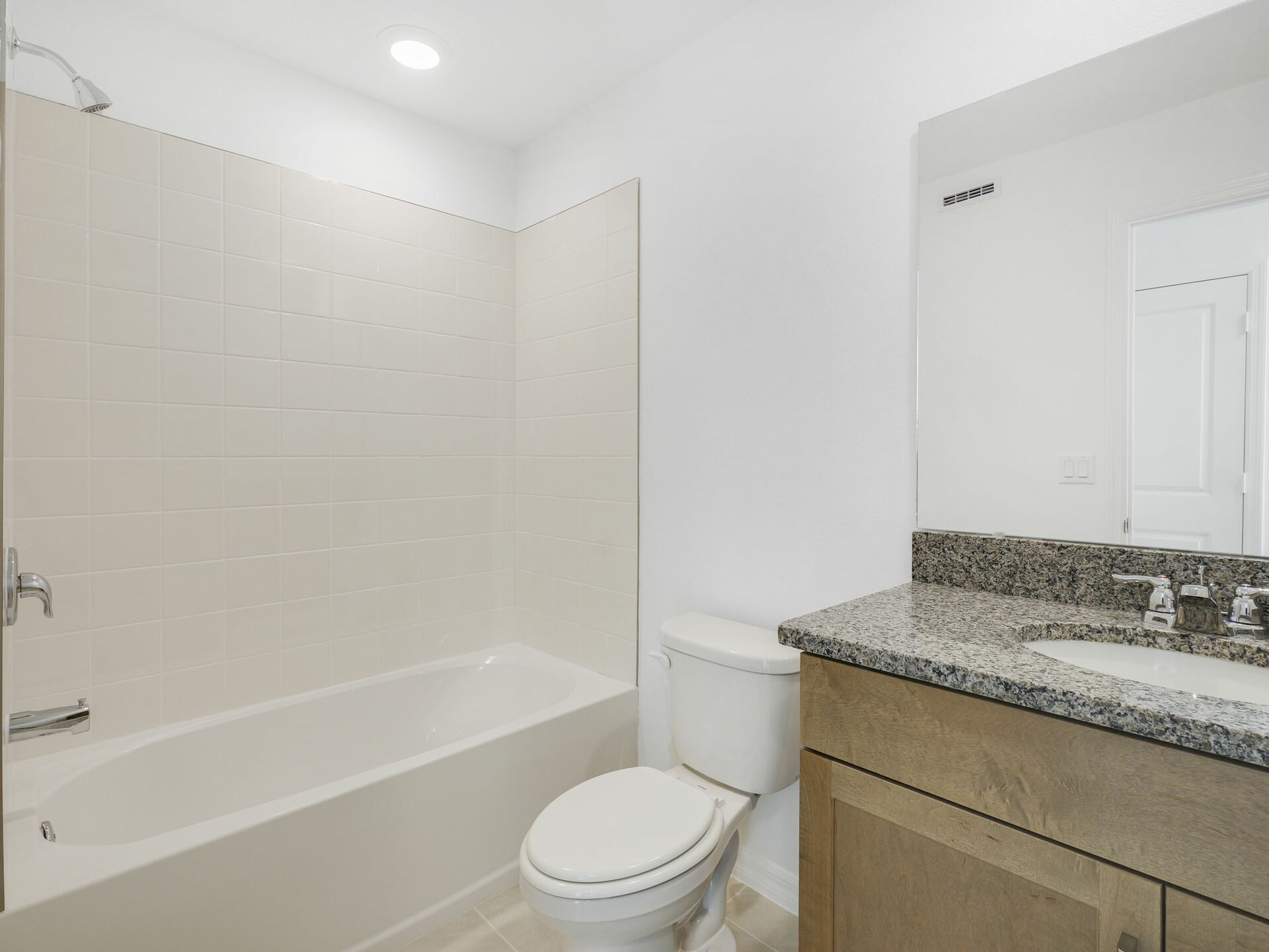 second bathroom with brown cabinets and granite countertops